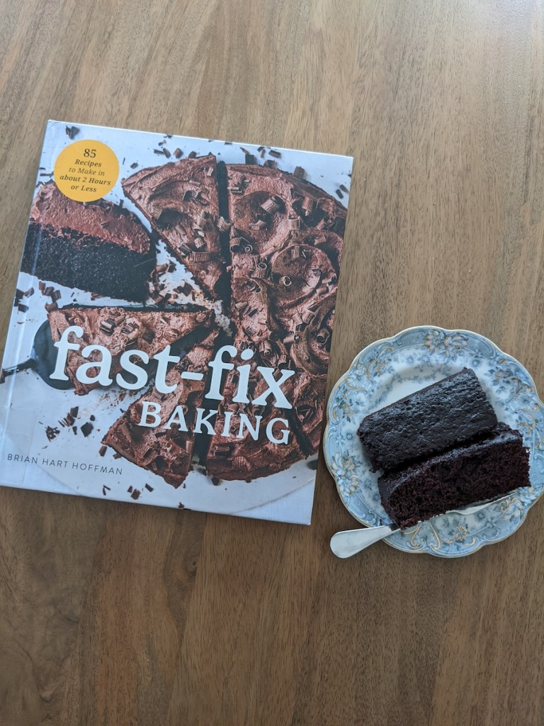 Photo of book Fast-Fix Baking with a chocolate cake on the cover next to a plate of two chocolate cake slices.